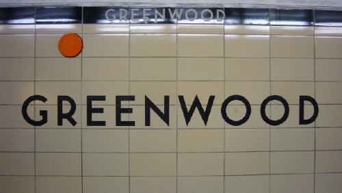 Tile wall reads GREENWOOD, with an orange dot near the black strapline at the top