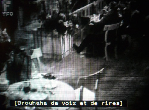 Black-and-white still frame with French caption reading [Brouhaha de voix et de rirres]