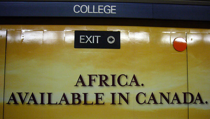 Wall shows COLLEGE and EXIT → signs and billboard copy reading AFRICA. AVAILABLE IN CANADA