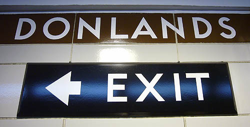 DONLANDS in bright white letters on black strapline at top of wall, EXIT sign in enamelled steel