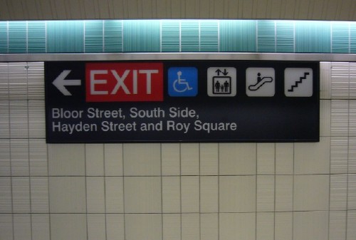 Sign in ‘Helvetica’ has arrow, EXIT, four pictographs, and legend Bloor Street, South Side, Hayden Street and Roy Square