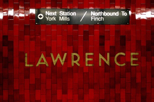 Letters blasted into deep red-black tiles read LAWRENCE