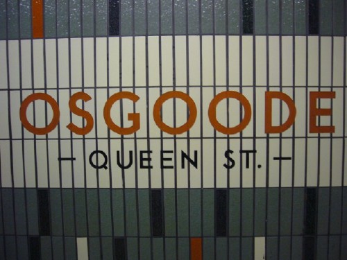 Sign reads OSGOODE in red TTC font and — QUEEN ST. — in black, set against cream-coloured vertical tiles
