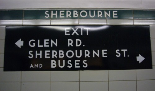 White letters on a black sign read EXIT ← GLEN RD. SHERBOURNE ST. AND BUSES →