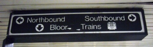 Sign with arrows cut out of circles is very widely spaced and reads Northbound Southbound Bloor Trains