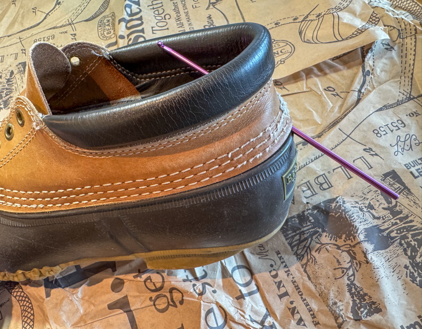 Duckboot with orange spool of thread pushed all the way through the heel