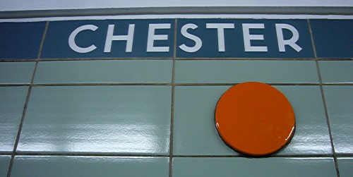 CHESTER in white letters on green strapline; green tiles with orange dot