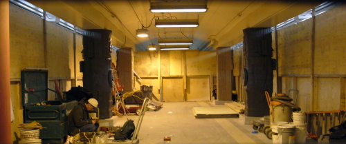 Enclosed work area has some covered and some uncovered caryatids and a workman crouching on the floor
