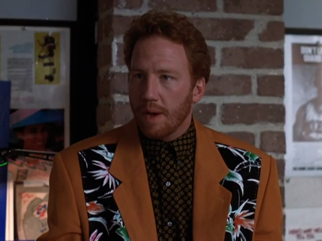 Elliot in russet blazer with black insets of tropical flowers behind the lapels