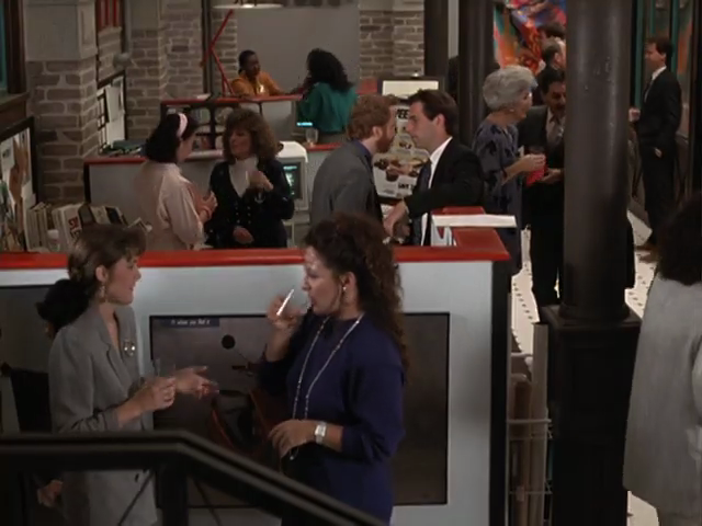 High-up view of busy office with exposed brick, orange partition-wall tops