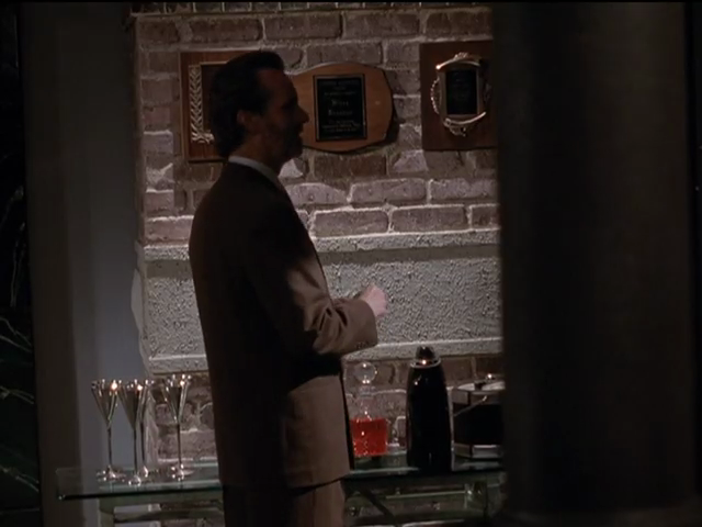 Miles alongside wet bar in office, with plaques mounted on exposed-brick wall