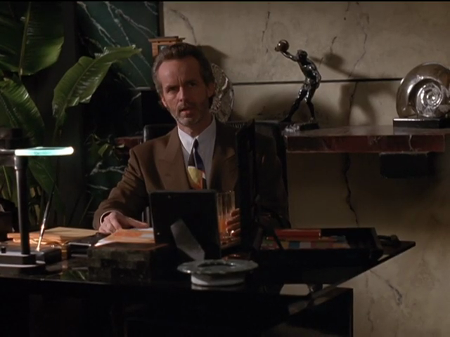 Miles Drentell in office, with mottled panelling behind him