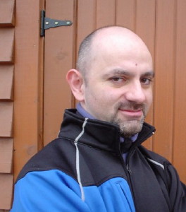 Me in black jacket with blue patch, photographed against brown door