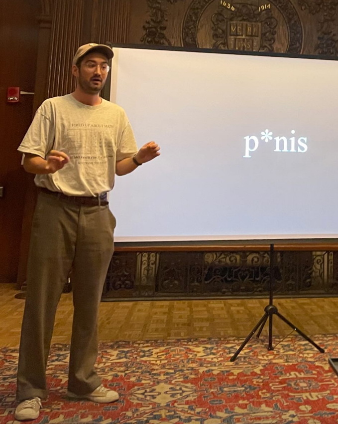 Aleksic before projected slide reading p*nis